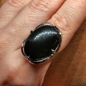 May include: A silver ring with a large oval black gemstone set in a silver bezel.