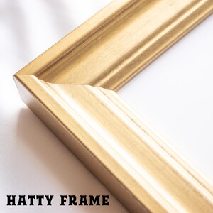 A close-up image of a gold-colored, ornate frame with a textured surface.