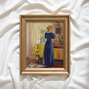 May include: A framed painting depicts a woman in a long blue dress standing before a mirror. The artwork features a gold frame and a warm color palette, with yellow flowers in a vase and on a table. The scene is set in a room with a window.