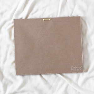 a blank, brown-colored piece of paper or card lying on a white, crumpled fabric surface.