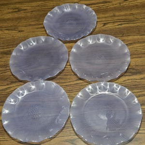 May include: Set of five light purple glass dinner plates with a textured, rippled design. The plates have a scalloped edge.