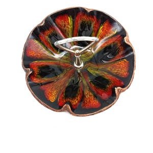 May include: A vintage, two-tiered serving dish with a vibrant, floral-like design. The dish features a black base with red, orange, and yellow accents. It has a silver metal handle and a copper-colored rim. The dish is likely made of ceramic or glass.