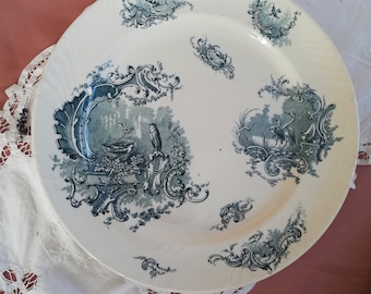 May include: A white ceramic plate with a blue and white floral design. The plate has a scalloped edge and is decorated with a floral pattern in shades of blue.
