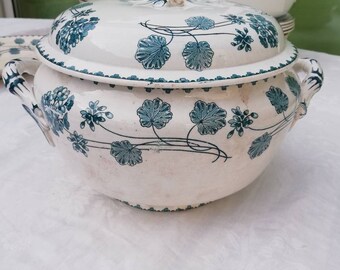 Puede incluir: Un plato de servir de cerámica blanca con tapa, con un diseño floral verde. El plato tiene dos asas a los lados y un borde elevado.