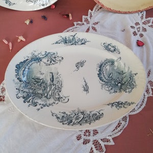 May include: A white oval serving platter with a blue and white floral design. The platter has a raised rim and a scalloped edge.