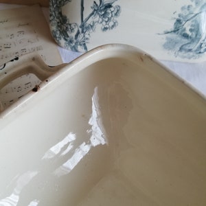 Op de afbeelding: De binnenkant van een witte keramische bakvorm met een glanzende afwerking. De vorm is vierkant en is leeg.