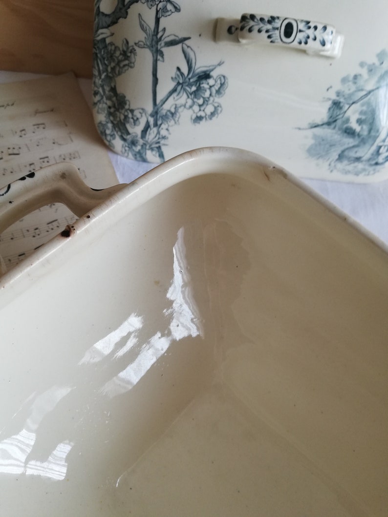 Op de afbeelding: De binnenkant van een witte keramische bakvorm met een glanzende afwerking. De vorm is vierkant en is leeg.