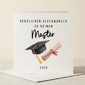 Könnte beinhalten: Eine weiße Abschlusskarte mit dem Text "HERZLICHEN GLÜCKWUNSCH ZU DEINEM Master" und dem Jahr 2026. Die Karte zeigt eine schwarze Abschlusskappe mit goldener Quaste und eine gerollte Urkunde mit rotem Band.