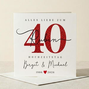 Op de afbeelding: Een witte kaart met de tekst "ALLES LIEBE ZUM 40 RUBIN HOCHZEITSTAG Birgit & Michael 1986 ❤️ 2026". Het getal 40 is in rode glitter, en de namen zijn handgeschreven.