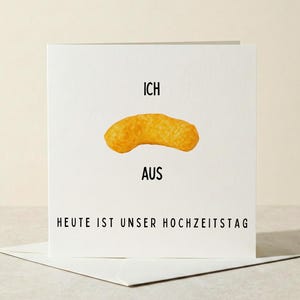 Könnte beinhalten: Eine quadratische weiße Grußkarte mit einer zentralen Grafik eines orangefarbenen Mais-Snacks. Der Text lautet ICH über dem Snack, AUS darunter und HEUTE IST UNSER HOCHZEITSTAG am unteren Rand in einer schwarzen serifenlosen Schriftart.