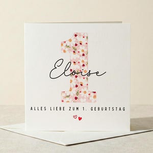 Può includere: Un biglietto d'auguri quadrato bianco con un grande numero uno riempito da un motivo floreale rosa. Il nome Eloise è scritto in corsivo nero al centro. Sotto, il testo recita ALLES LIEBE ZUM 1. GEBURTSTAG con due piccoli cuori rossi.