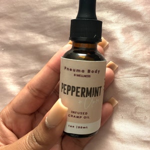 May include: A brown glass bottle with a black dropper top. The label reads "Pneumma Body & Wellness" and "Peppermint + Clary" in a white font. The bottle contains infused cramp oil and is 1 oz (30 ml).