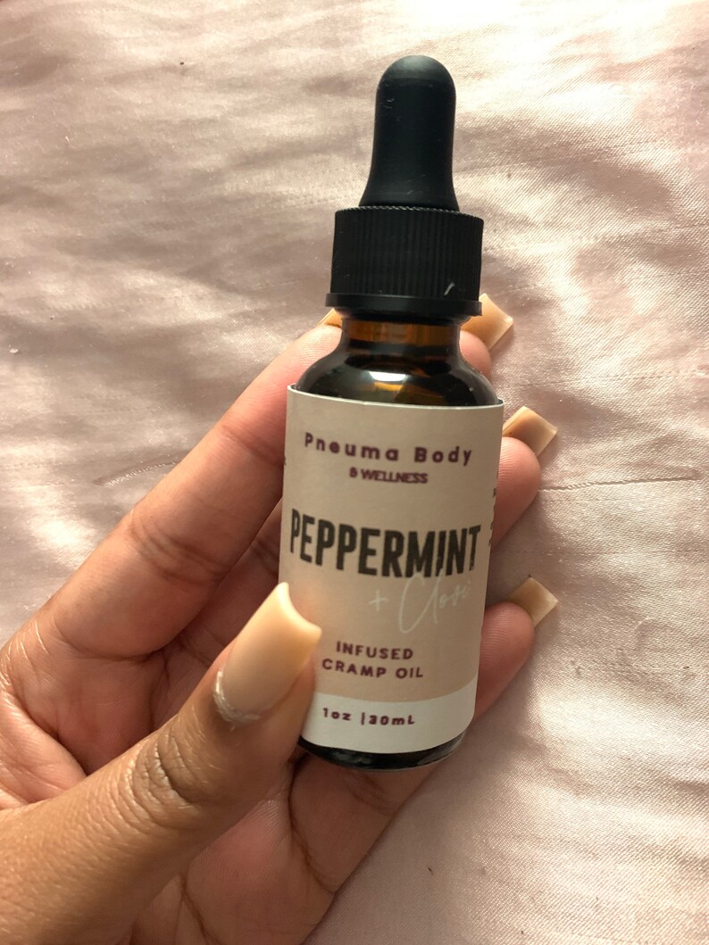 May include: A brown glass bottle with a black dropper top. The label reads "Pneumma Body & Wellness" and "Peppermint + Clary" in a white font. The bottle contains infused cramp oil and is 1 oz (30 ml).