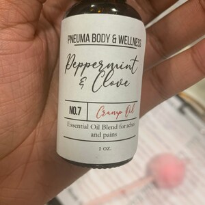 May include: A small brown glass bottle with a white label that reads "PNEUMA BODY & WELLNESS Peppermint & Clove NO.7 Cramp Oil Essential Oil Blend for aches and pains 1 OZ."