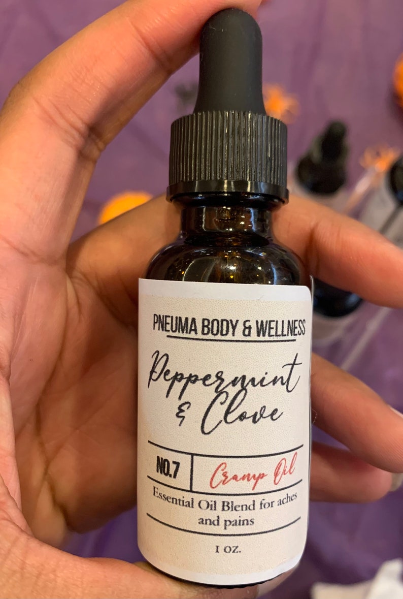 May include: A brown glass bottle with a black dropper top and a white label. The label reads "PNEUMA BODY & WELLNESS Peppermint & Clove NO.7 Cramp Oil Essential Oil Blend for aches and pains 1 OZ."