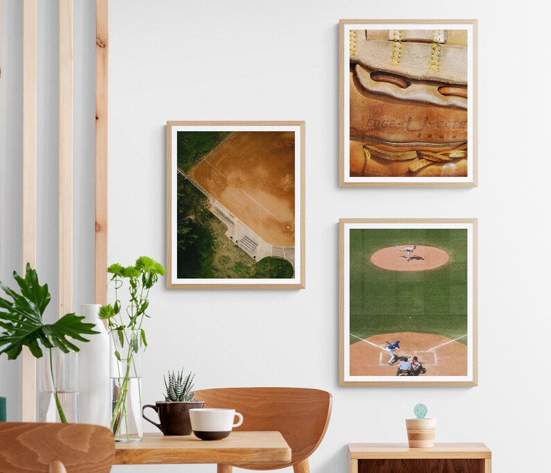 K&ouml;nnte beinhalten: Drei gerahmte Baseball-Prints. Der obere Druck zeigt eine Nahaufnahme eines braunen Leder-Baseballhandschuhs mit wei&szlig;en N&auml;hten und dem Text "Edge & Leather" in Wei&szlig;. Der mittlere Druck zeigt eine Luftaufnahme eines Baseballfeldes mit gr&uuml;nem Gras und einem braunen Innenfeld. Der untere Druck zeigt ein laufendes Baseballspiel mit Spielern in blauen und wei&szlig;en Uniformen auf einem gr&uuml;nen Feld.