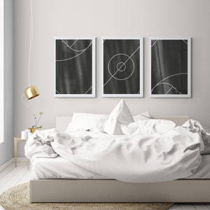 May include: Three black and white geometric abstract art prints in white frames hanging above a white bed with white bedding.