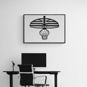 May include: Black and white photograph of a basketball hoop hanging from a ceiling. The hoop is made of metal and has a net. The photo is framed and hanging on a white wall.