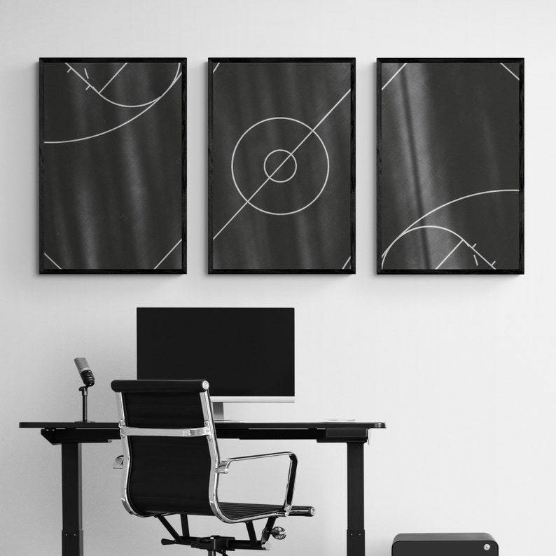 May include: Three black framed prints with white geometric designs on a black background. The prints are hanging on a white wall above a black desk with a black computer monitor, a black chair, and a black speaker.