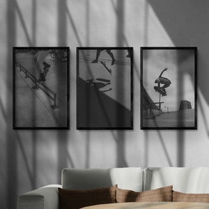 Puede incluir: Tres fotograf&iacute;as enmarcadas en negro de patinadores haciendo trucos. Las fotos est&aacute;n colgadas en una pared blanca con sombras de una ventana.