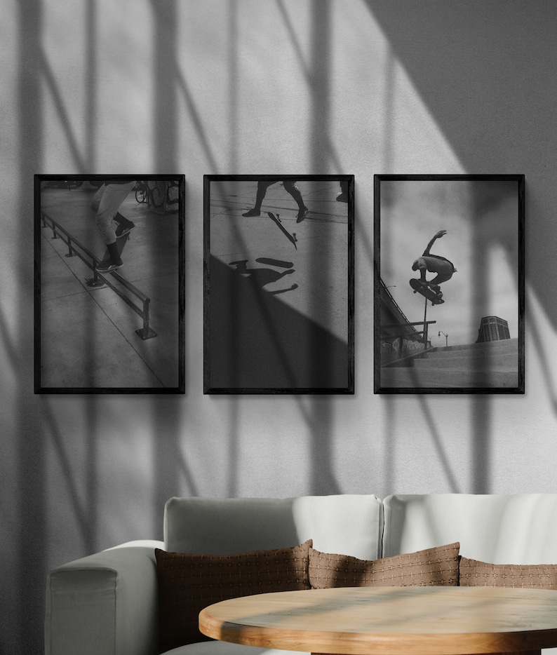 Puede incluir: Tres fotograf&iacute;as enmarcadas en negro de patinadores haciendo trucos. Las fotos est&aacute;n colgadas en una pared blanca con sombras de una ventana.