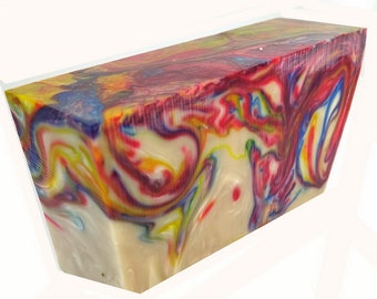 May include: A rectangular block with a swirling pattern of colors including red, yellow, blue, and white. The block has a smooth, polished surface and a creamy white base color. The colors blend together in a marbled effect.