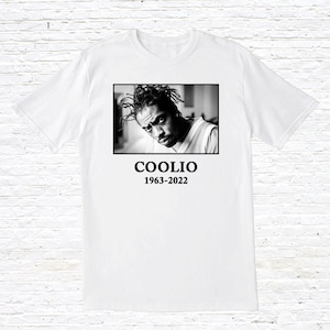 May include: A white t-shirt with a black and white photo of Coolio on the front. The text "COOLIO 1963-2022" is printed below the photo.