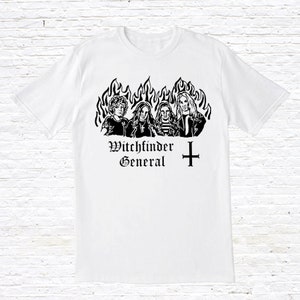 Könnte beinhalten: Weißes T-Shirt mit einem schwarz-weißen Grafikdruck einer Band namens "Witchfinder General". Die Grafik zeigt vier Personen vor Flammen und einem Kreuz.