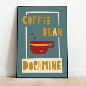Puede incluir: Una lámina decorativa rectangular en un marco negro con fondo verde azulado, una taza de café roja con una franja amarilla, dos granos de café marrones y el texto COFFEE BEAN DOPAMINE con la palabra ITALY impresa en letras pequeñas.