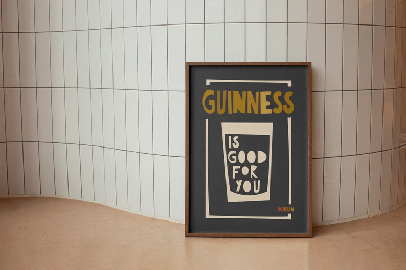 Op de afbeelding: Een ingelijste poster met een zwarte achtergrond en witte tekst die "GUINNESS IS GOOD FOR YOU DUBLIN" luidt. De tekst is in een vetgedrukt, gestileerd lettertype. Een witte omtrek van een glas Guinness bevindt zich in het midden van de poster.
