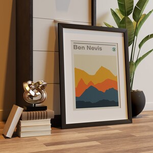 May include: A black framed print with the text "Ben Nevis" and a stylized mountain landscape in shades of orange, yellow, blue, and brown.