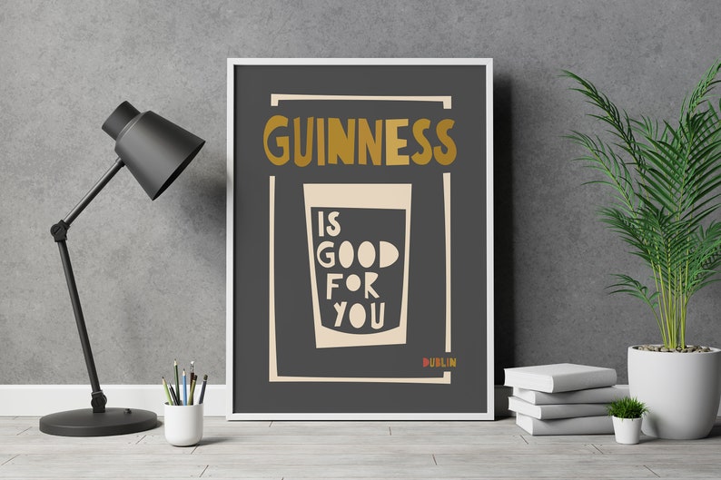 Op de afbeelding: Een zwart-witte poster met de tekst "GUINNESS IS GOOD FOR YOU" in een gouden lettertype. De poster bevat ook een glas Guinness met een witte achtergrond en het woord "DUBLIN" in een gouden lettertype.