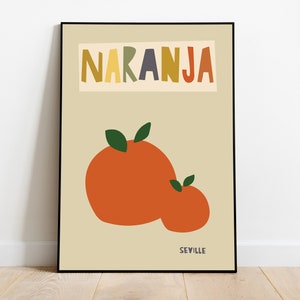 Puede incluir: Una lámina enmarcada con fondo beige que muestra dos frutas de color naranja, cada una con dos hojas verdes. La palabra NARANJA aparece en letras grandes y multicolores en la parte superior, y la palabra SEVILLE en letra pequeña abajo.