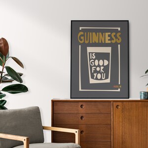 Op de afbeelding: Een zwart-witte poster met de tekst "GUINNESS IS GOOD FOR YOU" in een gouden lettertype. De poster toont ook een glas Guinness met het woord "DUBLIN" onderaan.