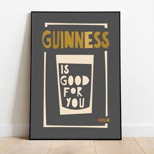 Op de afbeelding: Een zwart-witte poster met de tekst "GUINNESS IS GOOD FOR YOU" in een gouden lettertype. De poster bevat ook een glas Guinness en het woord "DUBLIN" in een rood lettertype.