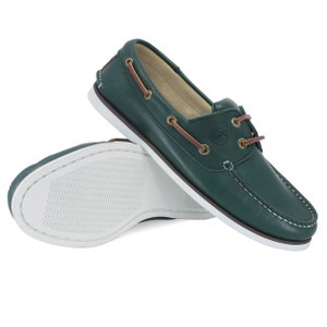 Puede incluir: Un par de zapatos n&aacute;uticos de cuero verde con suelas blancas y cordones marrones. Los zapatos tienen un logotipo dorado en el lateral.