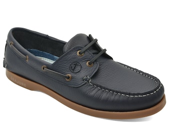 May include: Navy blue leather boat shoes with a brown rubber sole and a white stitched trim. The shoes have a lace-up closure and a small anchor logo on the side. The brand name "Seajure" is printed on the sole.