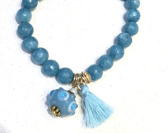 Peut inclure: Un bracelet en perles bleu clair avec un charme en verre bleu et blanc et un pompon bleu clair.