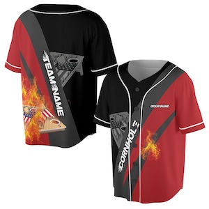 Può includere: Maglia da baseball nera e rossa con una striscia diagonale grigia. La maglia ha un tabellone di cornhole e fiamme sul davanti. Il testo "CORNHOLE" è scritto sulla maglia. Il testo "TEAM NAME" è scritto sull'altro lato della maglia.