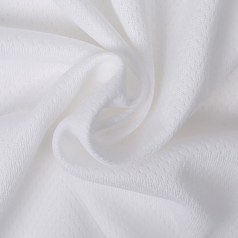 May include: White fabric with a smooth, textured surface. The fabric is folded and draped, showing its soft and flowing texture.