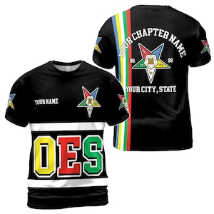 Puede incluir: Camiseta negra con una franja blanca y las letras "OES" en amarillo, rojo y verde. La camiseta presenta un emblema de estrella y el texto "YOUR NAME" en la parte delantera. La parte trasera muestra "YOUR CHAPTER NAME" y "YOUR CITY, STATE".