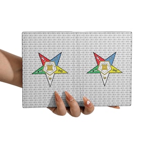 Puede incluir: Un bolso de mano rectangular con un patrón repetido de las letras "OES". El bolso presenta dos emblemas en forma de estrella con un diseño central, en rojo, azul y dorado. El fondo es blanco.