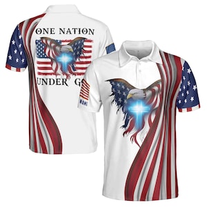 May include: White polo shirt with a red, white, and blue American flag design. The flag features a bald eagle with a cross in the center. The text "ONE NATION UNDER GOD" is printed on the shirt.