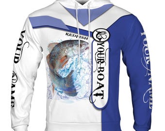 Könnte beinhalten: Weißer Hoodie mit blau-weißem Design. Der Hoodie zeigt einen Rotbarsch, der aus dem Wasser springt, mit dem Text "YOUR BOAT" auf der rechten Seite und "REDFISH" auf der linken Seite. Die Ärmel haben den Text "YOUR NAME" auf der linken und "YOUR NAME" auf der rechten Seite.