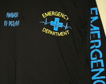 May include: Black long-sleeve t-shirt with a blue and yellow graphic of a cross and a heartbeat with the text "EMERGENCY DEPARTMENT". The right sleeve has the word "EMERGENCY" printed vertically in blue.