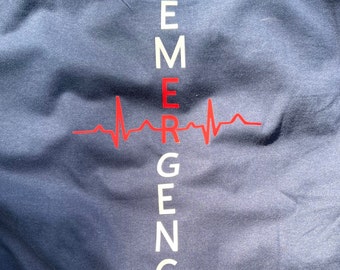 Puede incluir: Una camiseta azul marino con un gráfico vertical blanco que dice "EMERGENCY" con un gráfico de latido del corazón rojo en el medio.