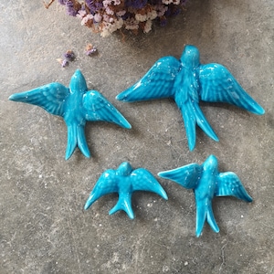 Puede incluir: Cuatro piezas de decoración de pared de golondrina de cerámica azul. Las aves están en vuelo y tienen un acabado texturizado.