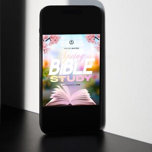 May include: A black smartphone displays a colorful graphic for a Spring Bible Study. The design features pink flowers, a bright open book, and the words "Spring Bible Study" in large, bold letters. The text "Wednesdays 6PM" is also visible.