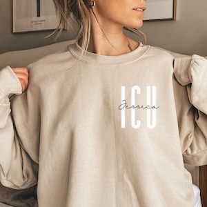 May include: A beige sweatshirt with the text "ICU Jessica" printed on the front.