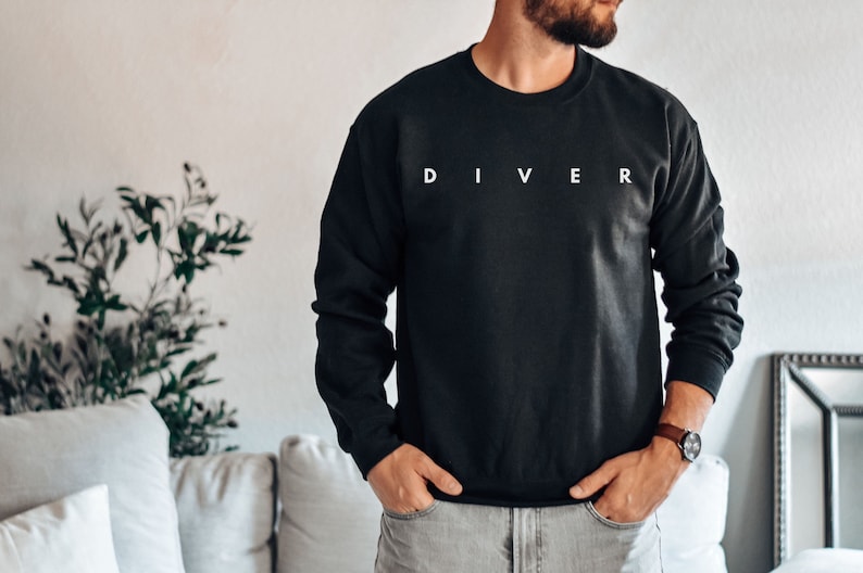 Puede incluir: Una sudadera negra de manga larga con la palabra "DIVER" impresa en blanco en la parte delantera.